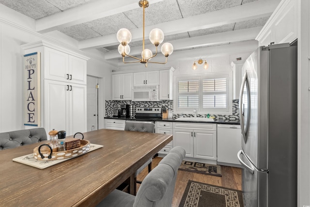 kitchen featuring backsplash, dark countertops, white cabinets, dark wood finished floors, and stainless steel appliances