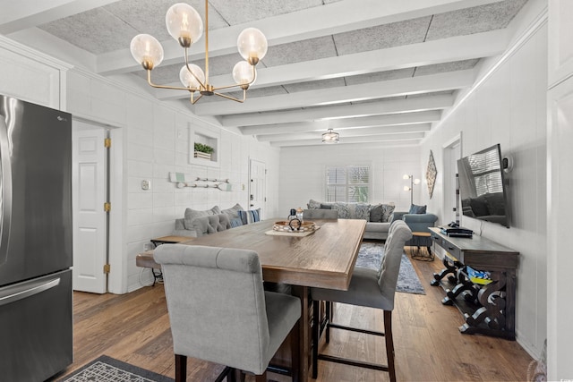 dining space with beamed ceiling, tile walls, a chandelier, and wood finished floors