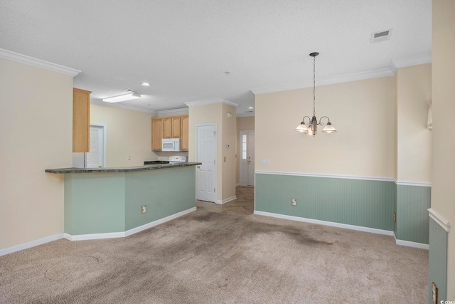 kitchen featuring visible vents, ornamental molding, dark countertops, white microwave, and carpet flooring