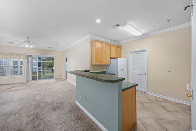 kitchen with a textured ceiling, freestanding refrigerator, crown molding, dark countertops, and visible vents