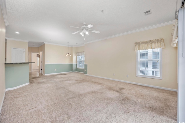 empty room with crown molding, ceiling fan with notable chandelier, light colored carpet, visible vents, and baseboards