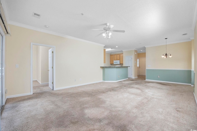 unfurnished living room featuring visible vents, baseboards, crown molding, ceiling fan with notable chandelier, and light colored carpet