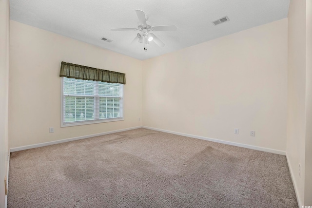 carpeted spare room with visible vents, ceiling fan, and baseboards