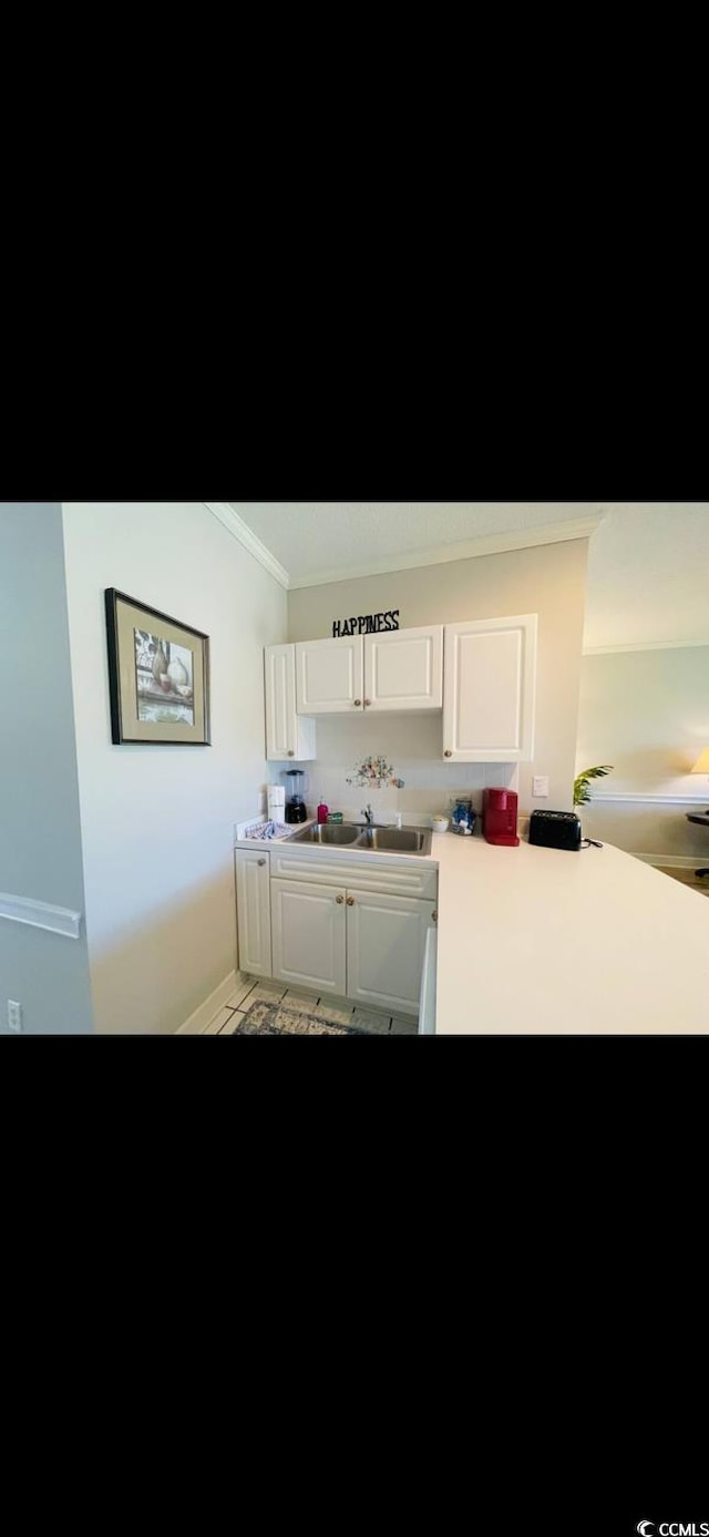 4669 Wild Iris Dr Unit 22-2O2, Myrtle Beach, SC 29577 - kitchen featuring white cabinets, a sink, light countertops, ornamental molding, and a peninsula