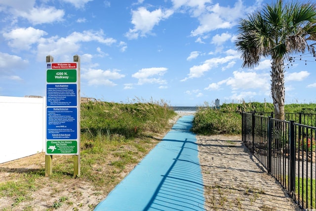view of home's community featuring fence and view of water and beach