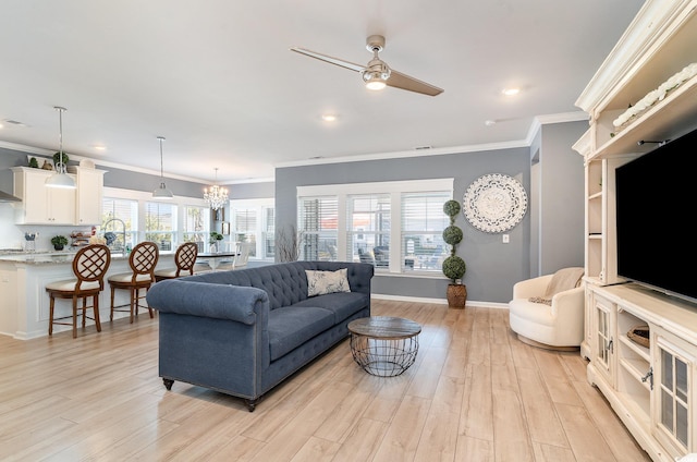 living area featuring crown molding, light wood-style flooring, and ceiling fan with notable chandelier