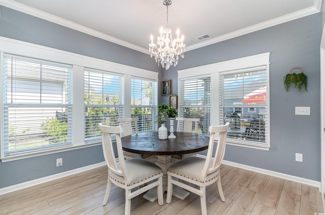 dining space featuring an inviting chandelier, light wood-style flooring, visible vents, baseboards, and ornamental molding