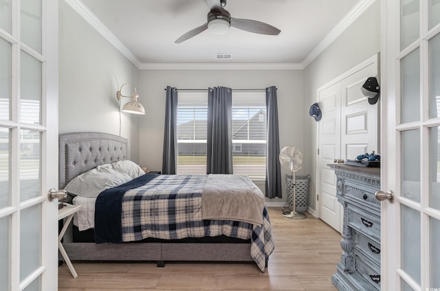 bedroom featuring light wood-type flooring, crown molding, visible vents, and a ceiling fan
