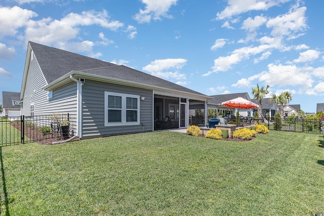 rear view of house featuring a fenced backyard, a sunroom, a shingled roof, and a yard