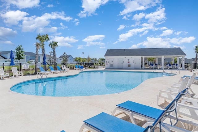 community pool with fence, a patio area, and a residential view