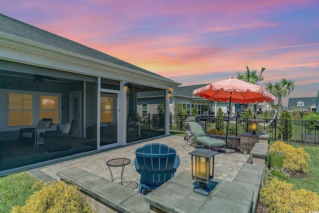 view of patio / terrace with a fire pit, a sunroom, and fence