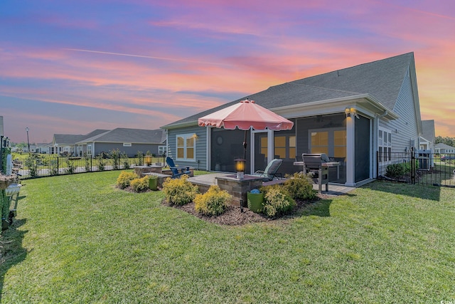 rear view of property featuring a lawn, a patio, a sunroom, and a fenced backyard