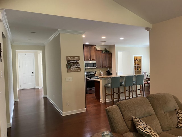 kitchen featuring appliances with stainless steel finishes, ornamental molding, dark wood-style floors, and a kitchen breakfast bar