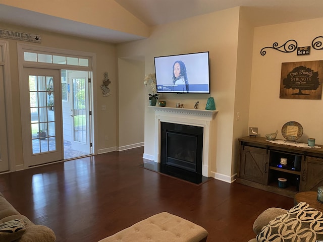 living area with a fireplace with flush hearth, baseboards, vaulted ceiling, and wood finished floors