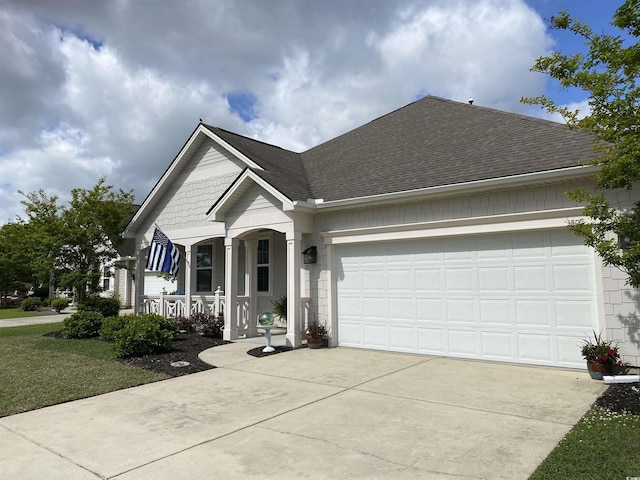 view of front of home featuring an attached garage, a shingled roof, covered porch, and driveway