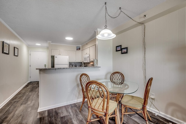 720 N Waccamaw Dr Unit 207, Garden City Beach, SC 29576 - dining space featuring baseboards, dark wood-type flooring, a textured ceiling, and ornamental molding