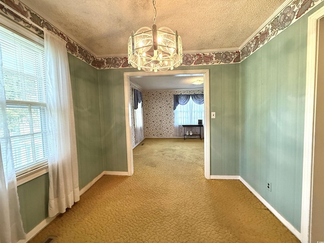 unfurnished dining area with baseboards, a textured ceiling, an inviting chandelier, and carpet floors