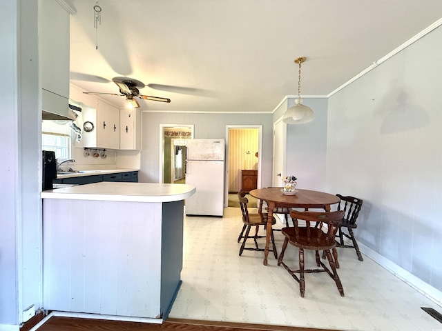 kitchen with freestanding refrigerator, light floors, a peninsula, a ceiling fan, and light countertops
