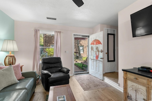 707 S 26th Ave S Unit L, North Myrtle Beach, SC 29582 - living room with light wood-type flooring, a textured ceiling, a ceiling fan, and baseboards