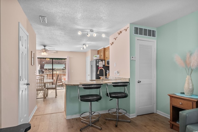 707 S 26th Ave S Unit L, North Myrtle Beach, SC 29582 - kitchen with freestanding refrigerator, a breakfast bar, light wood finished floors, a peninsula, and a textured ceiling