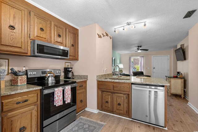 707 S 26th Ave S Unit L, North Myrtle Beach, SC 29582 - kitchen with stainless steel appliances, a sink, a peninsula, a ceiling fan, and brown cabinets