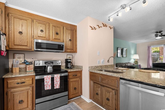 707 S 26th Ave S Unit L, North Myrtle Beach, SC 29582 - kitchen featuring appliances with stainless steel finishes, a sink, a textured ceiling, open floor plan, and brown cabinetry