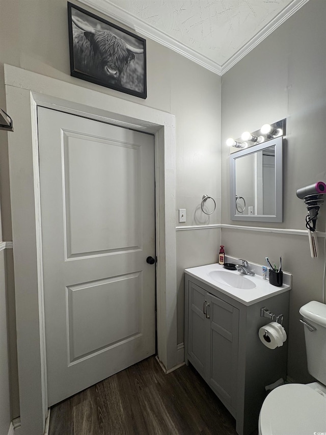 bathroom featuring wood finished floors, toilet, vanity, and ornamental molding