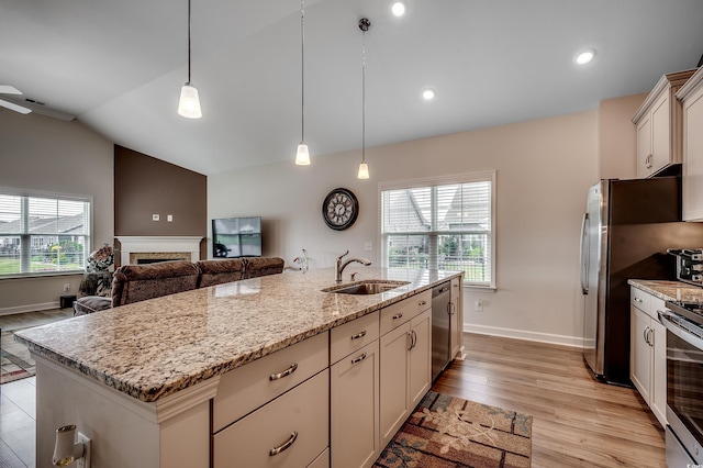 kitchen featuring light wood-style floors, appliances with stainless steel finishes, a sink, and pendant lighting