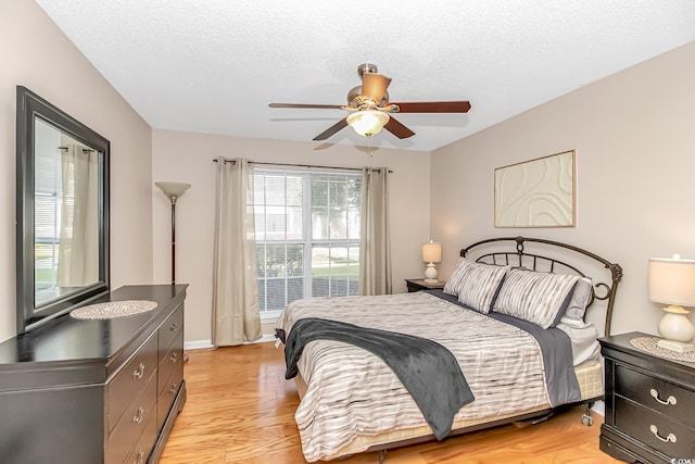 bedroom featuring light wood-type flooring, a textured ceiling, and a ceiling fan