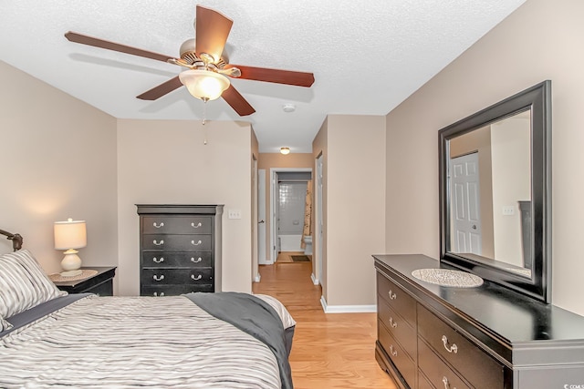 bedroom with ceiling fan, a textured ceiling, light wood-style floors, and baseboards