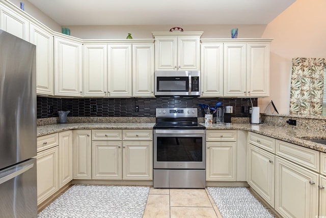 kitchen featuring appliances with stainless steel finishes, tasteful backsplash, light stone countertops, and light tile patterned flooring
