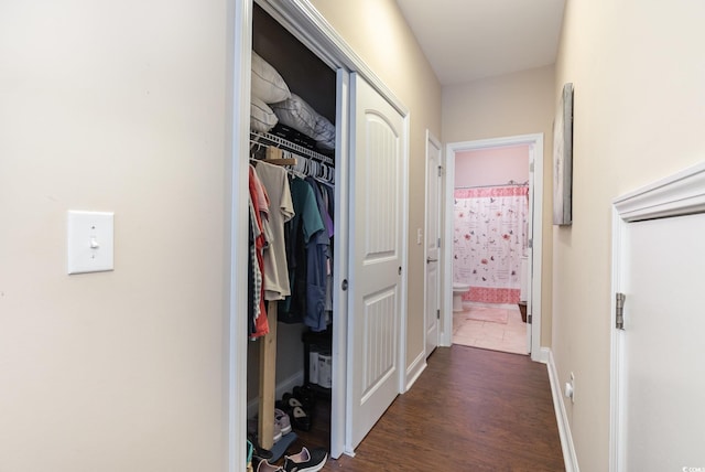 hallway featuring baseboards and dark wood-style floors