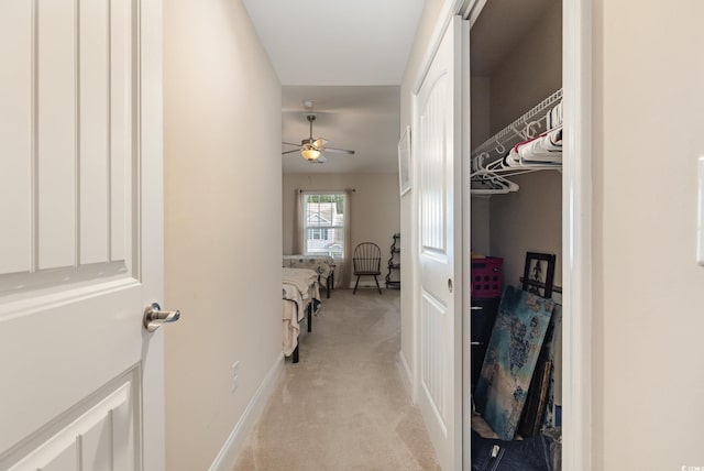 corridor featuring baseboards and light colored carpet