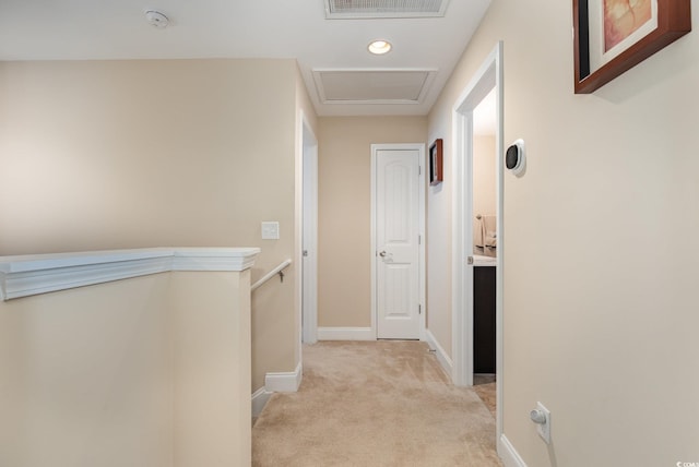 hall featuring attic access, visible vents, baseboards, an upstairs landing, and light carpet