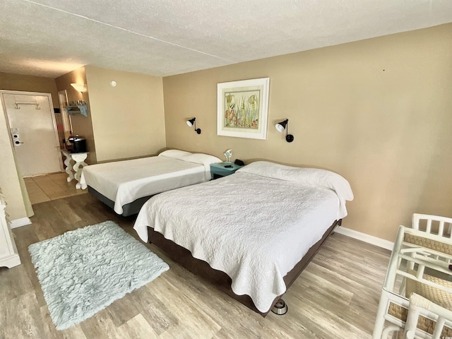 bedroom with wood finished floors, baseboards, and a textured ceiling