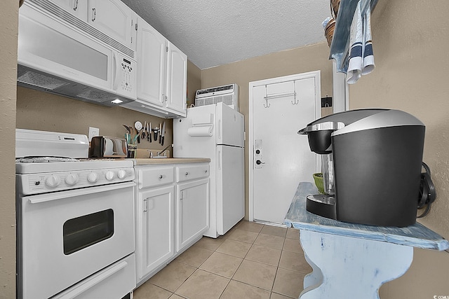 kitchen with white appliances, light tile patterned floors, white cabinetry, a textured ceiling, and a wall mounted AC