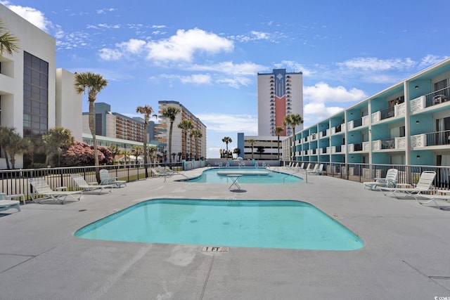 community pool with a patio and fence