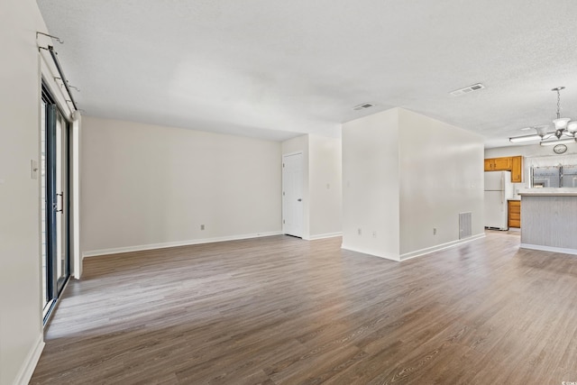 775 Plantation Dr Unit 87, Little River, SC 29566 - unfurnished living room with a chandelier, light wood-style floors, and a textured ceiling