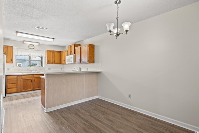 775 Plantation Dr Unit 87, Little River, SC 29566 - kitchen with a textured ceiling, a chandelier, wood finished floors, light countertops, and brown cabinets