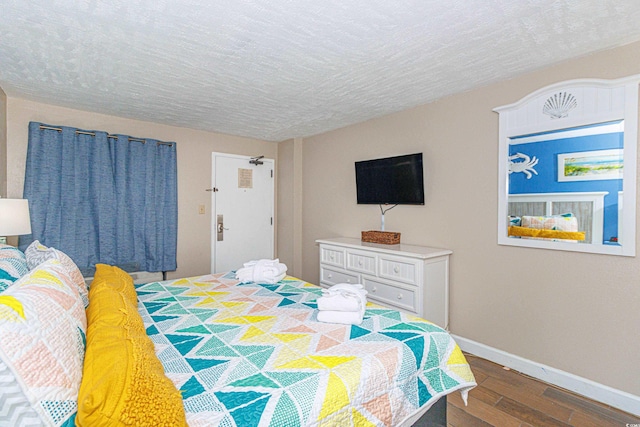 bedroom with baseboards, wood finished floors, and a textured ceiling