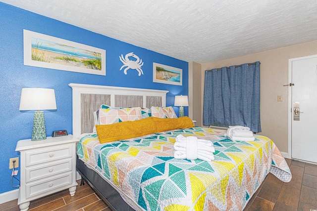 bedroom featuring wood finish floors, baseboards, and a textured ceiling