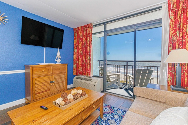 living room with baseboards, wood finished floors, a wall mounted air conditioner, and a water view