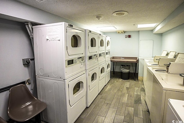 community laundry with stacked washing machine and dryer, washer and dryer, wood finished floors, and a textured ceiling