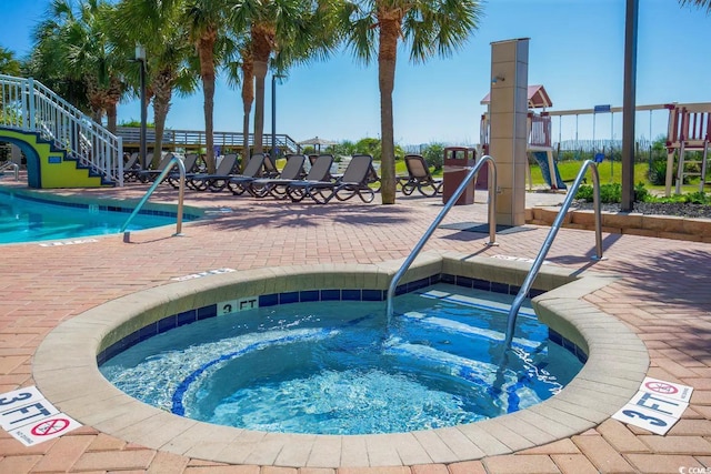 community pool with a patio area, a hot tub, and stairway