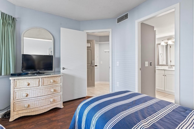 bedroom with wood finished floors, ensuite bathroom, and a sink
