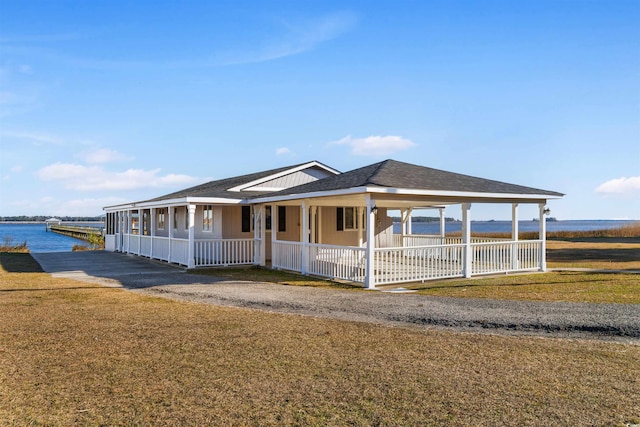 farmhouse featuring a porch, a water view, a front lawn, and a shingled roof