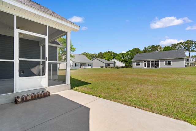 view of grassy yard with a patio area and a sunroom