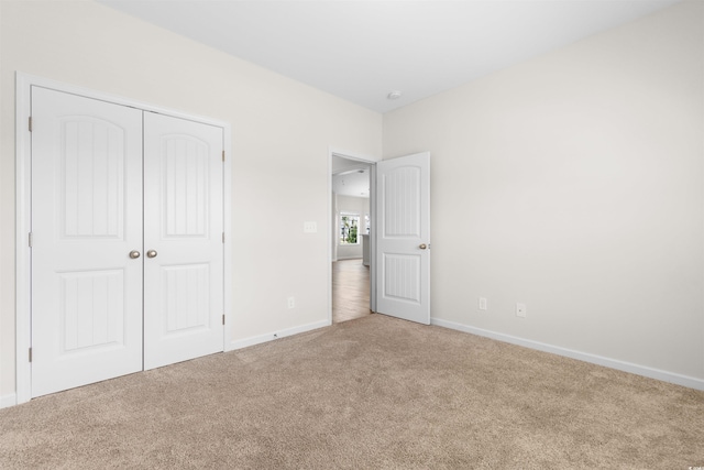 unfurnished bedroom with carpet, baseboards, and a closet