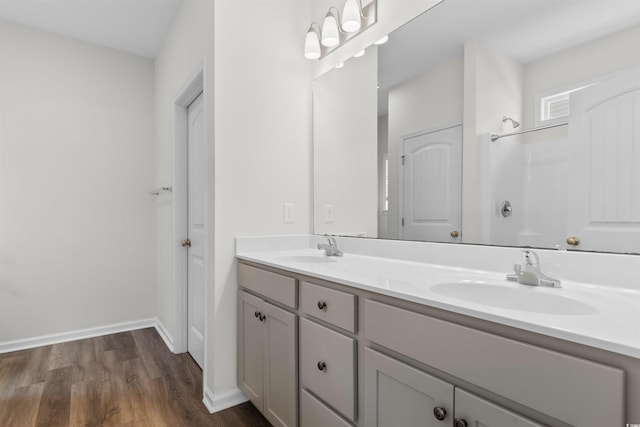 bathroom with wood finished floors, double vanity, and baseboards