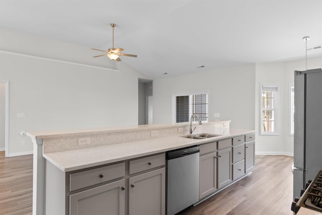 kitchen featuring stainless steel appliances, a sink, light wood-type flooring, a ceiling fan, and vaulted ceiling